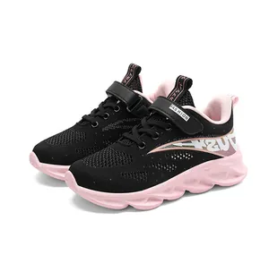Detalle de las zapatillas de malla negra para niñas con suelas onduladas rosas.