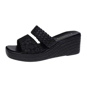 Close-up detail of black wedge sandals featuring a woven strap and floral pattern