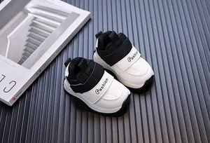 Detailed close-up of black and white leather baby sneakers on a dark textured background