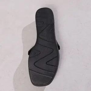 Detailed macro view of the black wedge sandal sole featuring non-slip zig-zag tread patterns
