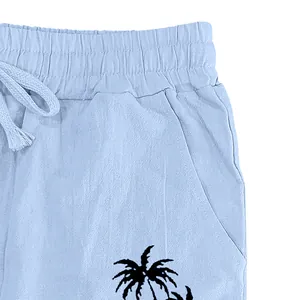 Close-up of men's blue linen pants featuring elastic waistband and palm tree print.
