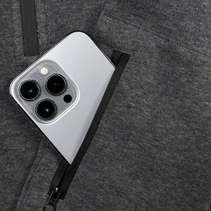 Macro view of a functional zippered arm pocket on a grey hoodie holding a large smartphone