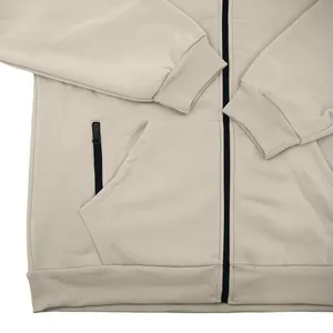 Détail d'un sweat à capuche en polaire beige pour homme avec poignets côtelés et poches zippées.