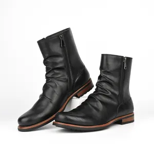 Detail view of black men's ankle boots featuring pleated leather and side metal zippers.
