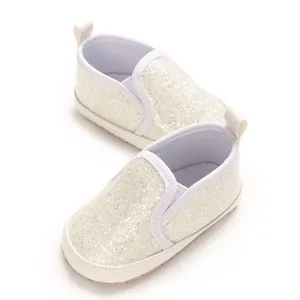 Detailed macro shot of sparkly white infant walking shoes with soft PU soles and pull tabs.
