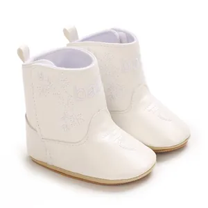 Close-up of elegant white baby boots with baby embroidery and heart detail on toe