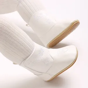 Macro view of white baby winter boots featuring delicate embroidered flowers and heart patterns