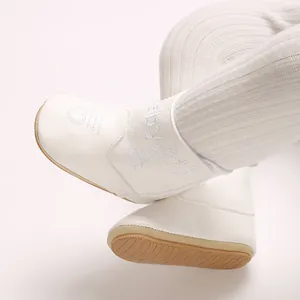 Close-up of white winter baby shoes with delicate embroidery and soft non-slip soles.