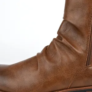Detail showing the textured pleated leather surface of brown men's slouchy boots.