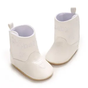 Detailed close-up view of white faux leather baby boots with embroidered heart design.