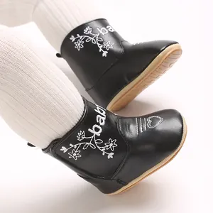 Close-up of black baby winter boots with white baby embroidery and floral details