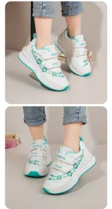 Dettaglio scarpe da ginnastica bianche per bambina con ricamo floreale verde e velcro.