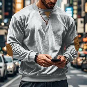 Detail of light gray men's corduroy sweatshirt with textured fabric and elbow patches.