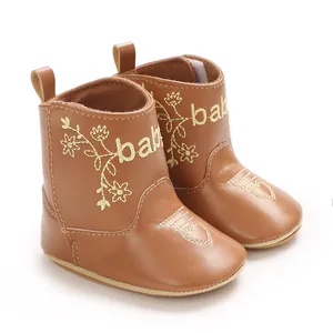Detailed macro view of brown faux leather baby boots featuring gold embroidery and heart design
