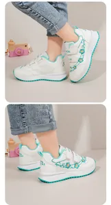 Vista dettagliata delle scarpe sportive bianche da bambina con ricamo floreale e accenti verdi.