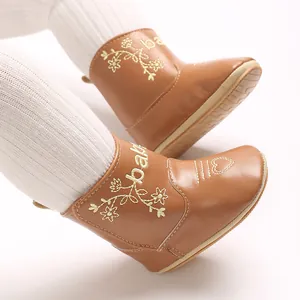 Detailed close-up of brown infant boots featuring floral embroidery and baby lettering