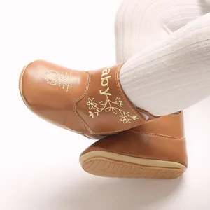 Close-up of tan leather baby shoes featuring delicate yellow heart and floral embroidery.