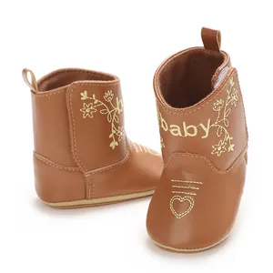 Close-up of brown baby boots with gold heart and flower embroidery