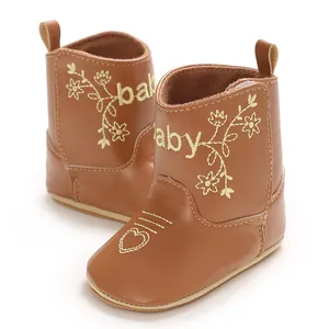 Close-up detail of brown British style baby boots featuring golden floral embroidery