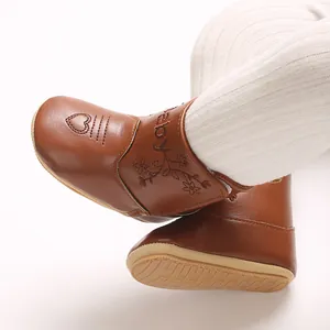 Close-up of brown baby leather boots with heart and floral embroidery details