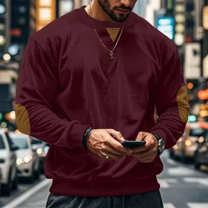 Close-up detail of men's burgundy corduroy crewneck sweatshirt with brown elbow patches