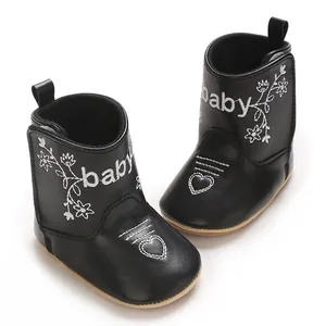 Detailed view of black faux-leather baby boots with white flower and heart embroidery.