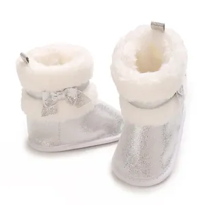 Close-up detail of silver glitter baby girl winter boots with white faux fur and bow