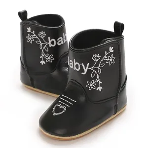 Detailed view of black infant boots with white floral embroidery and heart pattern.