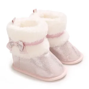 Detail of pink glitter baby girl winter boots with white faux fur and cute bow decoration.