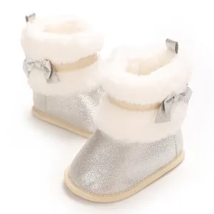 Close-up of silver glitter baby boots with white faux fur trim and a silver bow detail.