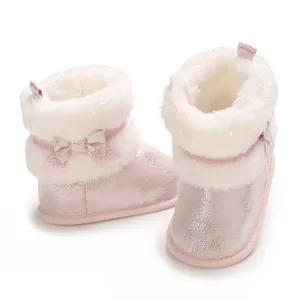Close-up detail of pink glittery baby boots featuring soft white faux fur lining and bow decoration
