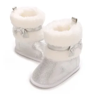 Detailed view of silver glittery baby boots with white faux fur and bow decoration