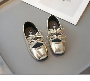 Nahaufnahme goldener Babyschuhe mit quadratischer Zehenpartie und Doppelschleife