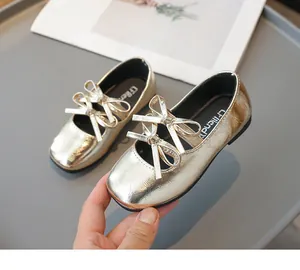 Detailaufnahme von glänzenden goldenen Mädchenschuhen mit eleganten Doppelschleifen