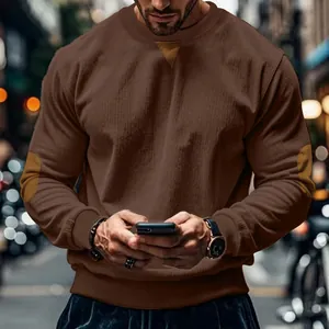 Macro view of a men's brown corduroy sweatshirt featuring stylish suede elbow patches
