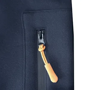 Detail shot of a navy blue hoodie sleeve zipper pocket with an orange cord puller