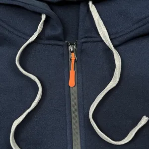 Close-up of navy hoodie showing black zipper with orange pull and grey drawstring