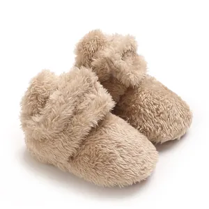 Nahaufnahme von weichen, dicken Korallenvlies-Babyschuhen in Hellbraun für Wärme im Winter