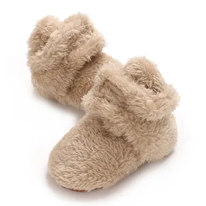 Weiche beige Korallenvlies Babyschuhe mit plüschiger Textur und rutschfester Sohle.