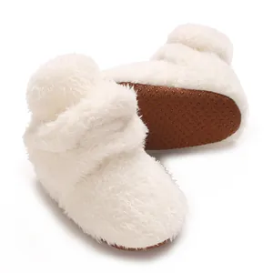 Nahaufnahme weißer Korallenfleece-Babyschuhe mit rutschfester, gepunkteter Gummisohle