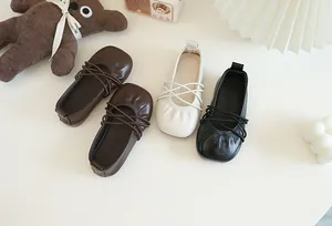 Detaillierte Nahaufnahme von weichen Leder-Ballerinas für Mädchen in Braun, Weiß und Schwarz.