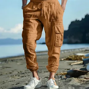 Men's brown cotton linen cargo pants with drawstring waist and pockets on beach