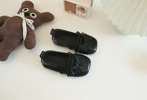 Draufsicht auf schwarze Mädchen-Ballerinas mit elastischen Riemen und weichen Sohlen.