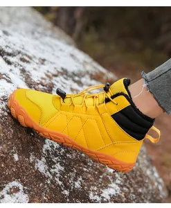 Detailed side view of yellow winter snow boots with warm fur lining on rock surface