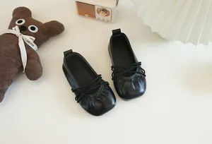 Elegante schwarze Leder-Ballerinas für Mädchen mit dekorativen Vintage-Requisiten.