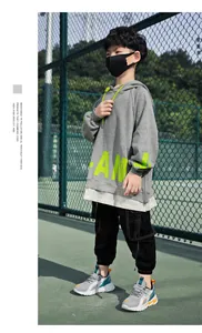 Graue, atmungsaktive Mesh-Laufschuhe für Jungen, von einem Modell getragen.