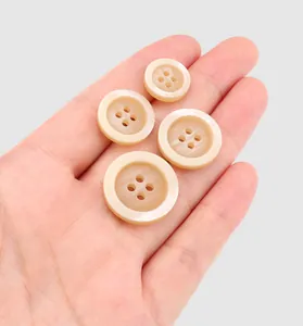 Gros plan de quatre tailles de boutons en résine crème de qualité supérieure dans une main