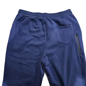 Detail view of men's navy fleece sweatpants showing the elastic waist and zipper pocket.