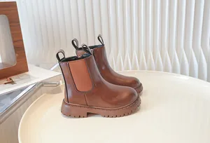 Professional side view of children's brown British style Chelsea boots on a minimalist white table