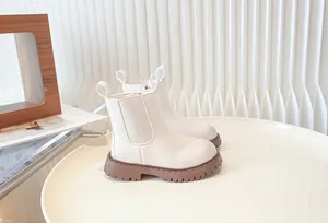 Close-up detail of cream white children's Chelsea boots featuring chunky brown soles